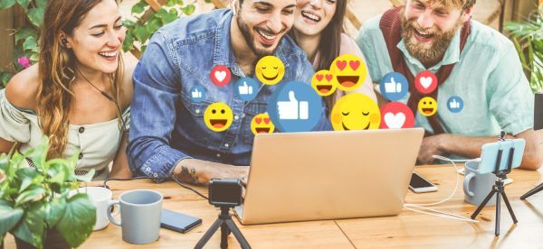 4 friends happily using a laptop together