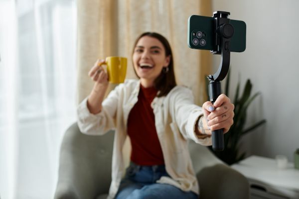 Woman talking a selfie with a mug using a selfie stick.