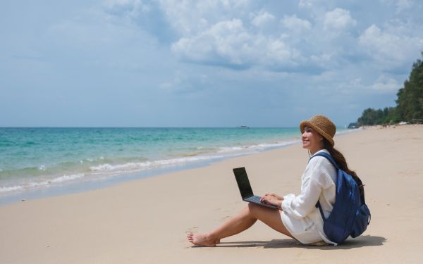 Woman sitting on a beach with her laptop