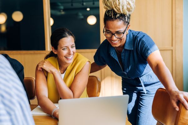 Two women laughing while looking at a laptop