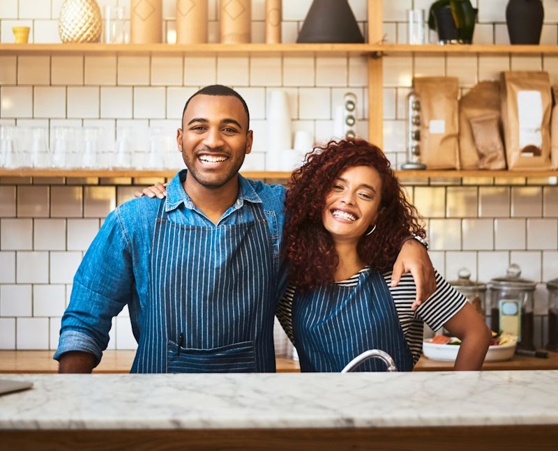 partners in aprons standing in a kitchen together