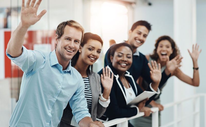 group of smiling people waving at the camera