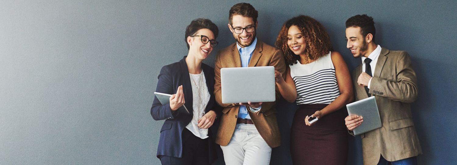 smiling people wearing business attire and looking at a laptop screen