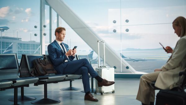 A man on his phone while waiting at the airport