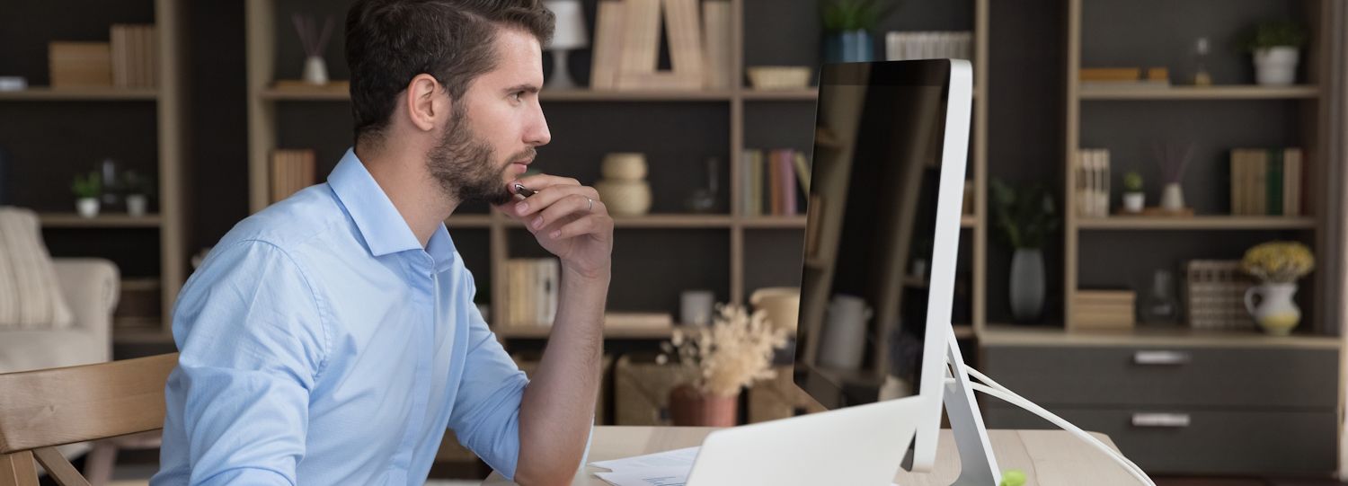 man in an office staring at the screen of a desktop computer