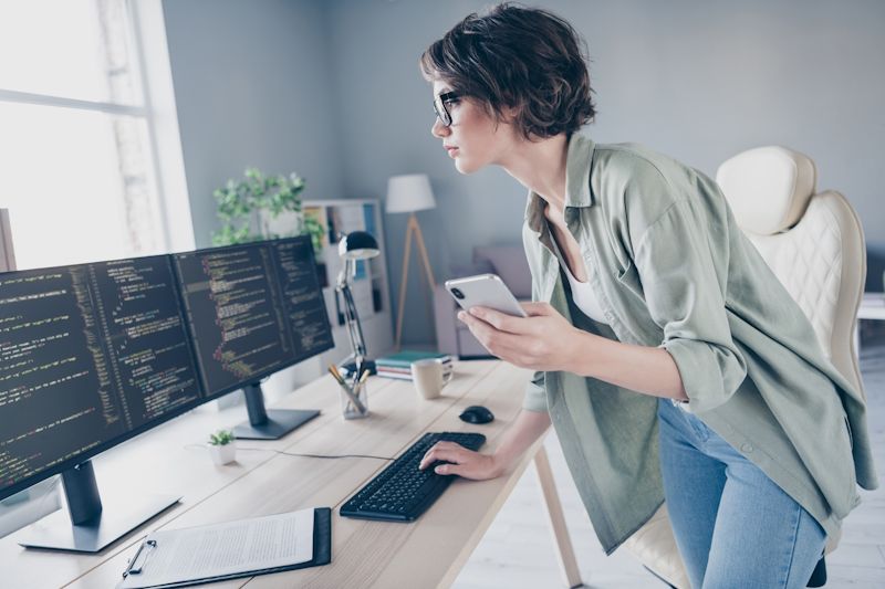 woman at a desk using a desktop computer and mobile device