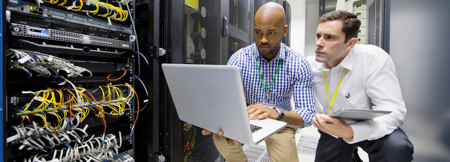 two it employees on a laptop by servers