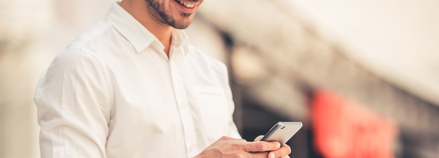 man smiling while typing on a mobile phone