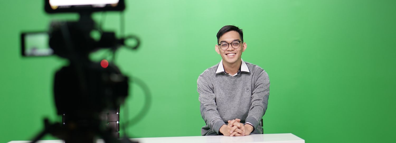 man filming a video with a green screen behind him